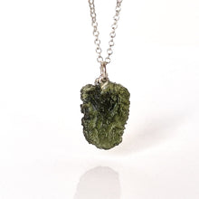 Load image into Gallery viewer, A silver chain necklace featuring a rough, organic-shaped olive green gemstone pendant, photographed against a clean white background with a soft reflection below.